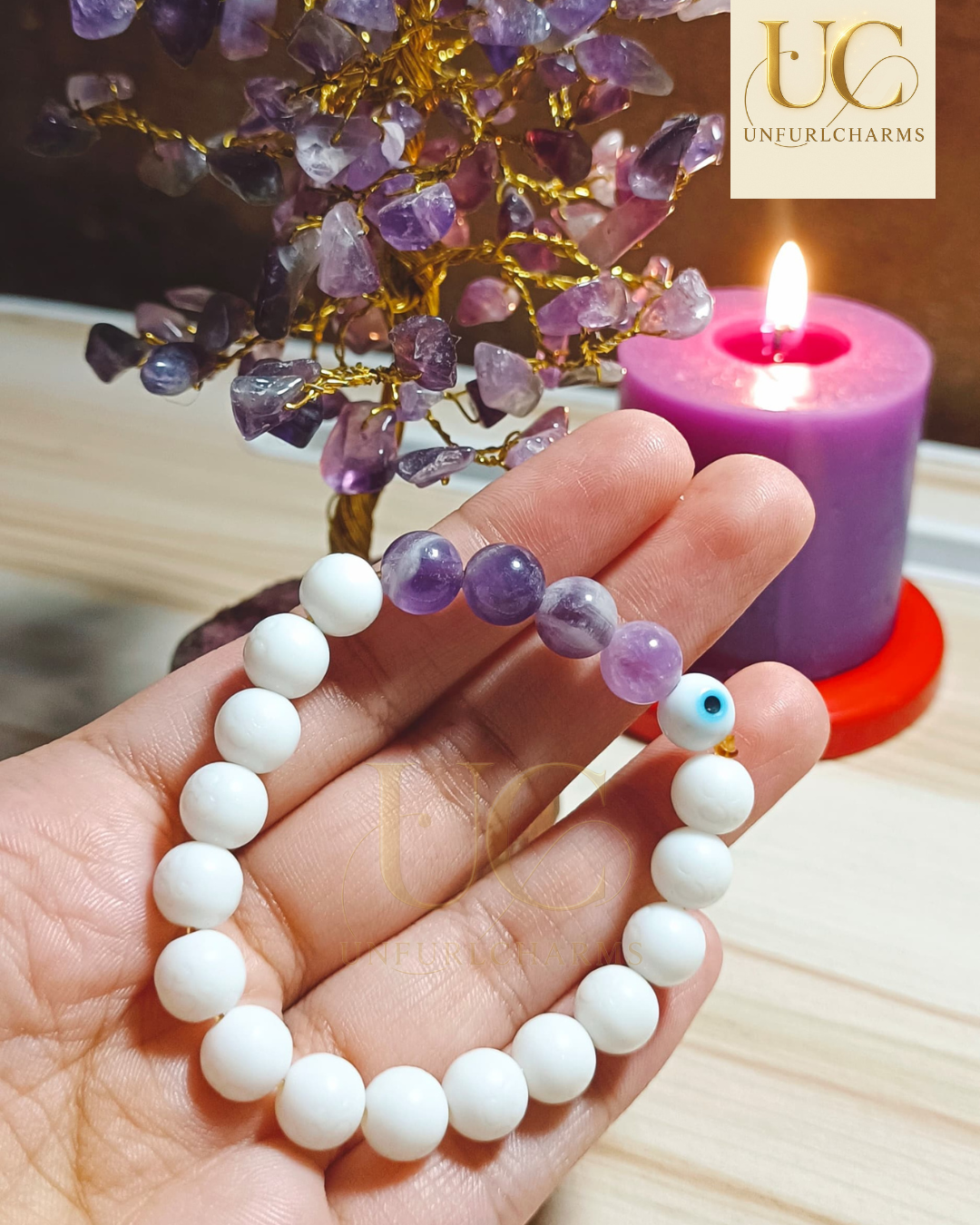 Hand holding a white beaded bracelet with purple beads, UnfurlCharms. Perfect for gifting purposes.